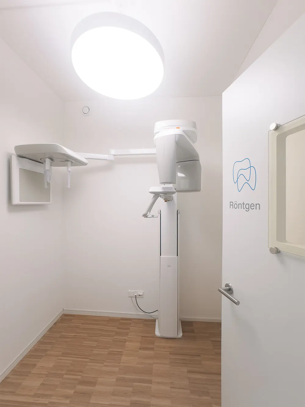X-ray room with a digital panoramic unit, the word Röntgen lettered on the wall